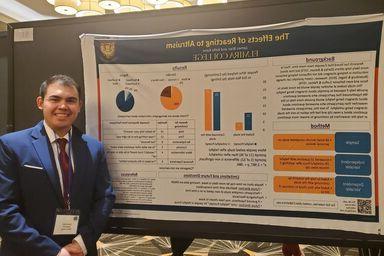 A male student stands with his presentation board during the Eastern Psychological Association Conference